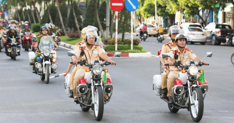 Một cảnh sát giao thông đang kiểm tra giấy tờ xe của người lái, thể hiện hoạt động tuần tra kiểm soát tuân thủ luật giao thông.
