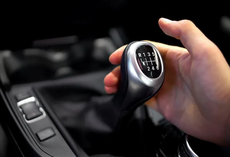 Một người lái xe ô tô số sàn đang thể hiện sự mệt mỏi khi di chuyển trong điều kiện giao thông tắc nghẽn, tay đặt trên cần số