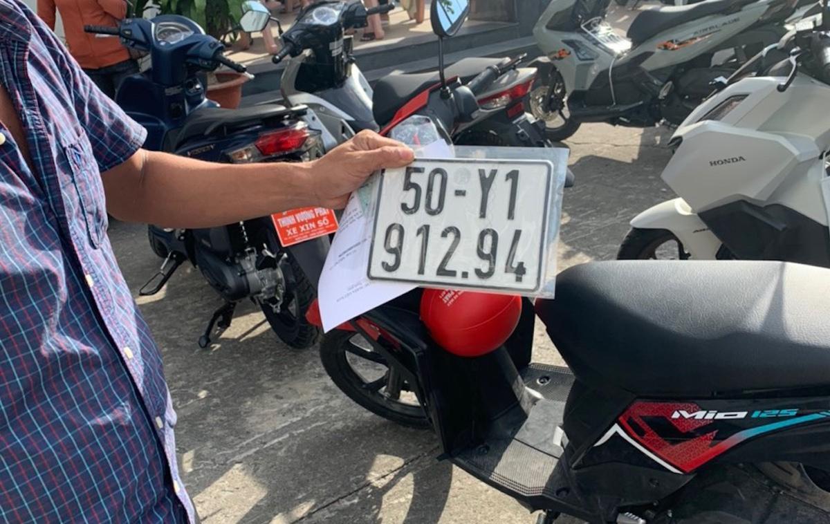 Hinh anh mot nguoi dung dang nhin vao nhieu tam bien so xe may khac nhau, the hien viec nhieu xe cung thuoc so huu cua mot nguoi voi cac bien so duoc dinh danh