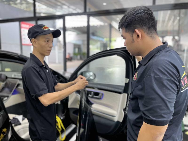 Kỹ thuật viên đang thi công dán phim cách nhiệt lên kính ô tô một cách cẩn thận