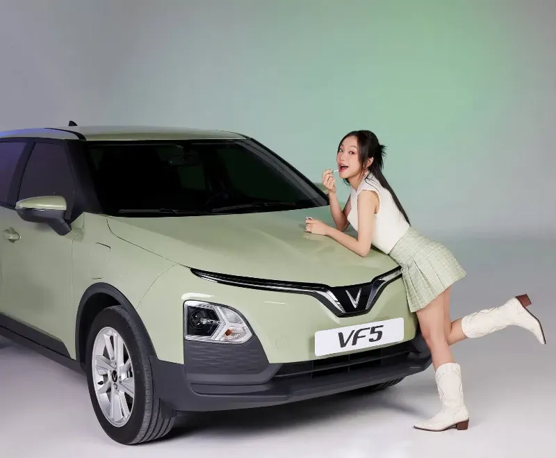 Xe Vinfast taxi màu xanh lá cây đặc trưng chạy trên đường phố đông đúc, thể hiện sự hiện diện của xe điện taxi
